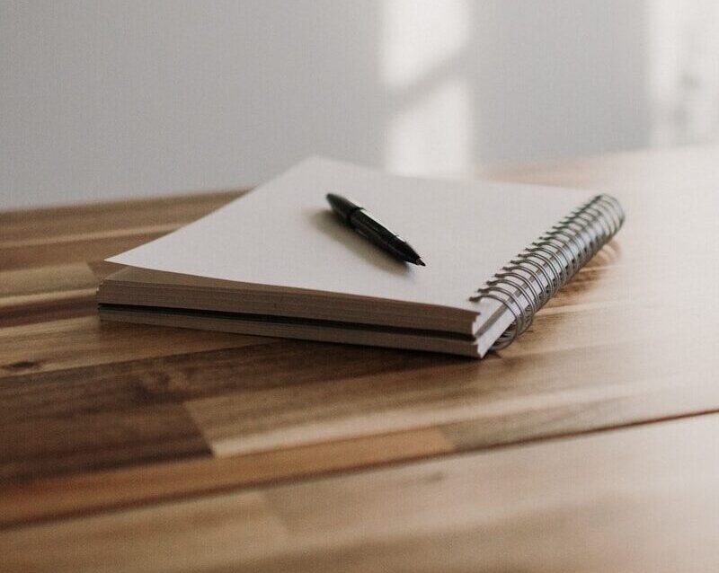 a notebook with a pen on top of a wooden table